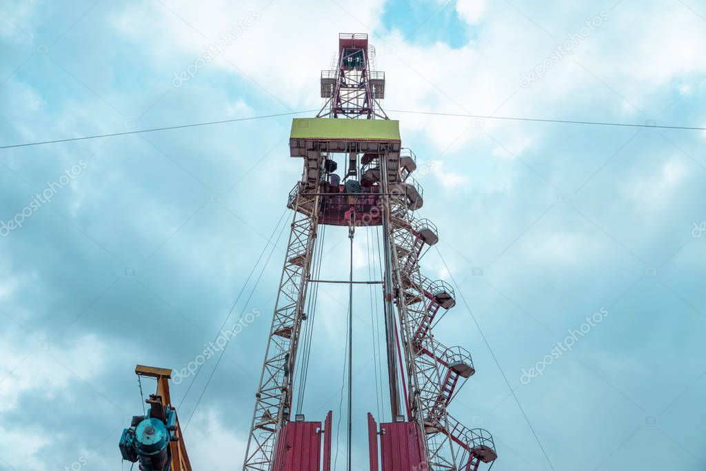 Oil and Gas Drilling Rig onshore dessert with dramatic cloudscape. Oil drilling rig operation on the oil platform in oil and gas industry.