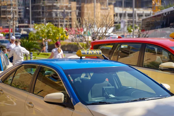 Imagen de un joven con gorra y camisa a cuadros sentado en el asiento trasero en taxi amarillo. Feliz macho subiéndose a un taxi. Empresario entrando en un taxi en la calle de la ciudad . — Foto de Stock