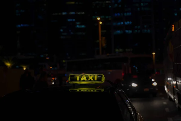 Gelbes Taxischild am Taxiwagen abends oder nachts in der Stadtstraße — Stockfoto