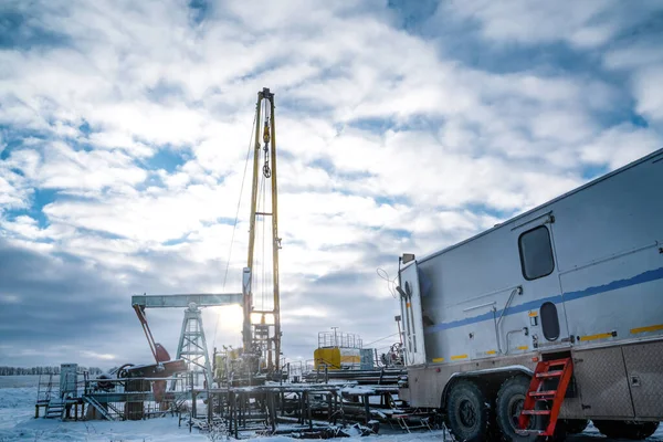Üst sürücüden sarkan kablosuz ağ ekipmanları ağaç kesimi için aşağıya inmeye hazır. Bir petrol kuyusu mühendisi, bir petrol kuyusunun içindeki çelik kaplamanın durumunu kaydetmek için uzman bir minibüsün arkasında çalışıyor.