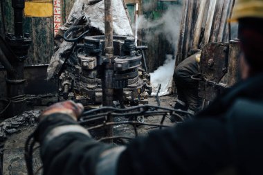 Offshore petrol kuyusu işçisi kuyu başındaki petrol kuyusunda delik açmak için alet ve ekipman hazırlayın. Sondaj borusu bağlantısı kuruyorum. Tribünlerin arasından matkap borusu bağlantısı için bir görünüm.