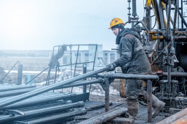 Offshore petrol kuyusu işçisi kuyu başındaki petrol kuyusunda delik açmak için alet ve ekipman hazırlayın. Sondaj borusu bağlantısı kuruyorum. Tribünlerin arasından matkap borusu bağlantısı için bir görünüm