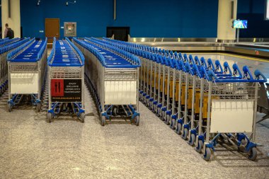 Ufa, Rusya 2 Nisan 2020: boş yük arabaları ve mavi duvarlı havaalanı tramvayı otoparkı. Modern havaalanında valizler.