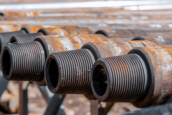 Oil Drill pipe. Rusty drill pipes were drilled in the well section. Downhole drilling rig. Laying the pipe on the deck. View of the shell of drill pipes laid in courtyard of the oil and gas warehouse. — Stock Photo, Image