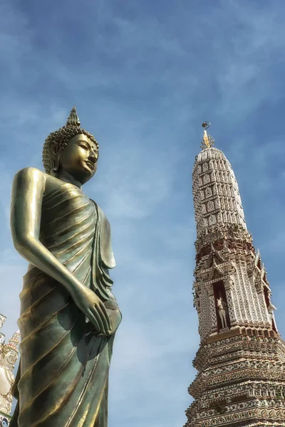 In Thailand, in Bangkok the Buddhist temple Wat Arun situated on the west bank of the Chao Phraya River is known as the Temple of the Dawn. View of a Buddha image with a Prang on the background