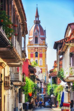 Kolombiya, Cartagena 'da balkonları Bougainvillia' da kaplanmış güzel bir kilise kulesi olan bir cadde.