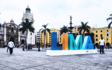 Lima, Peru - 28 Ocak 2020: Kasabanın merkezi olan Plaza Mayor 'daki Lima tabelasında poz veren turistler, yayalar ve sakinler. Basilica Katedrali en sonda.