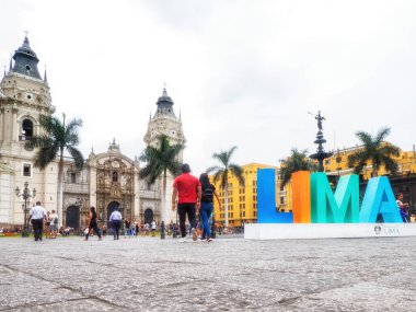 Lima, Peru - 28 Ocak 2020: Kasabanın merkezi olan Plaza Mayor 'daki Lima tabelasında poz veren turistler, yayalar ve sakinler. Basilica Katedrali en sonda.