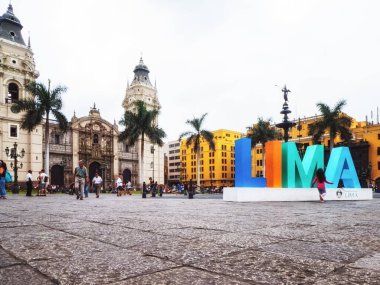 Lima, Peru - 28 Ocak 2020: Kasabanın merkezi olan Plaza Mayor 'daki Lima tabelasında poz veren turistler, yayalar ve sakinler. Basilica Katedrali en sonda.