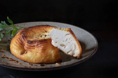 Koyu arkaplanda gri tabakta pişmiş ricotta peyniri, kapat.