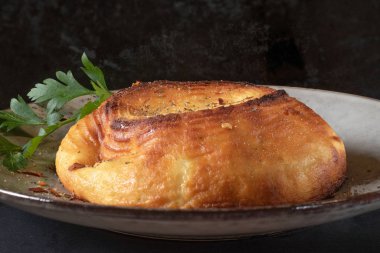 Koyu arkaplanda gri tabakta pişmiş ricotta peyniri, kapat.