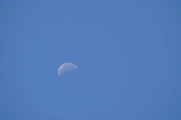 close-up shot of half moon in daytime blue sky