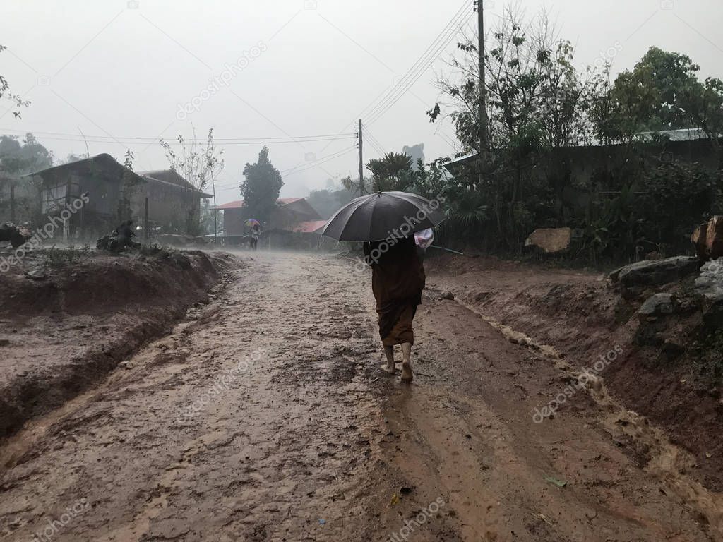 person walking on muddy rural road on rainy day
