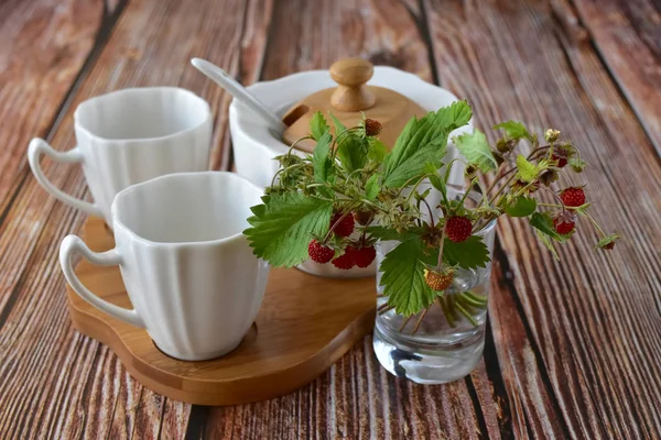 Delicate summer still life with a small bouquet of strawberries and a tea set