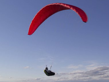 Bir paraglider atleti kırmızı bir paraglider uçurur..