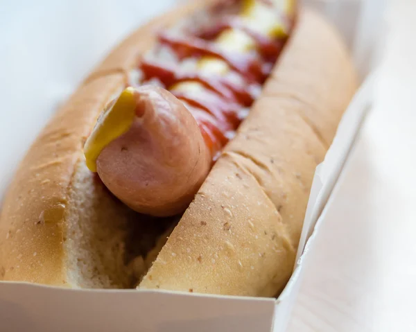 Hotdog com mostarda e ketchup em recipiente branco — Fotografia de Stock