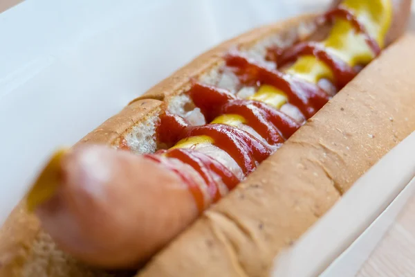 Hotdog com mostarda e ketchup em recipiente branco — Fotografia de Stock