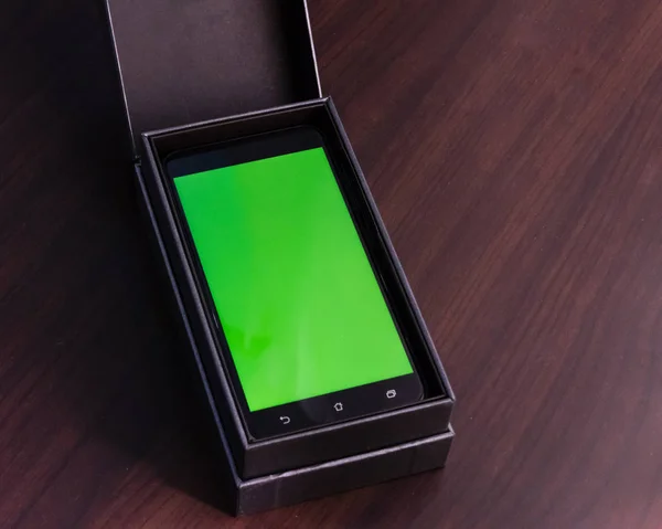 Teléfono inteligente con pantalla verde en caja — Foto de Stock
