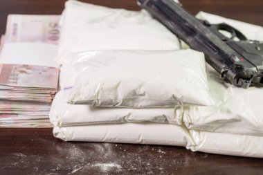 Bags of drugs, pistol and money on table clipart