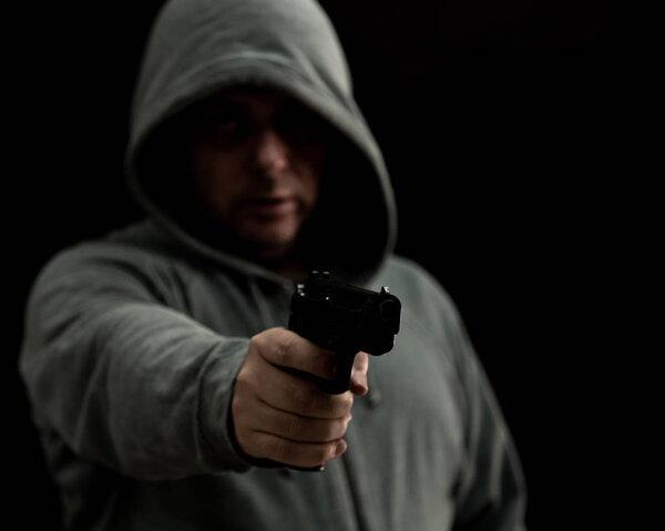 Thug in hoodie points gun