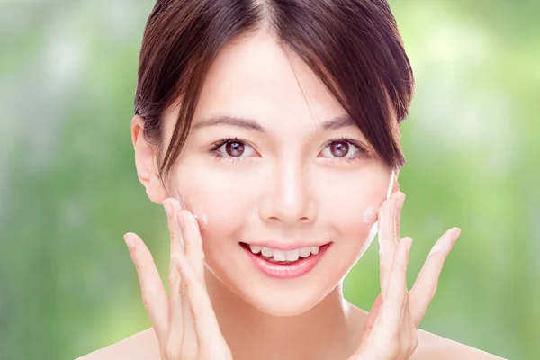 Beleza asiática aplicando creme no rosto — Fotografia de Stock