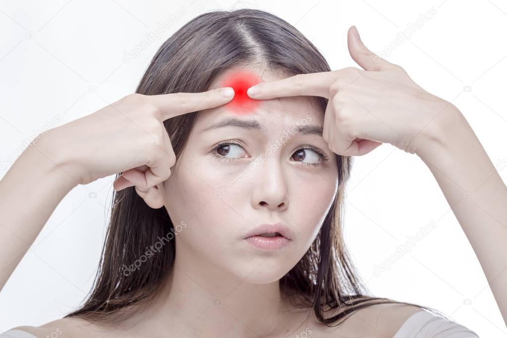 Asian woman squeezing glowing red spot on forehead