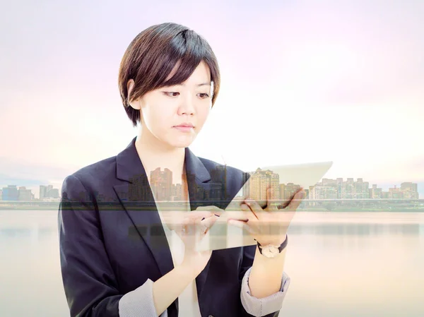 亚洲女商人，与城市景观的平板电脑上工作做 — 图库照片