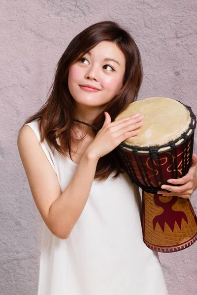 Asiática americana mujer jugando africano mano tambor — Foto de Stock