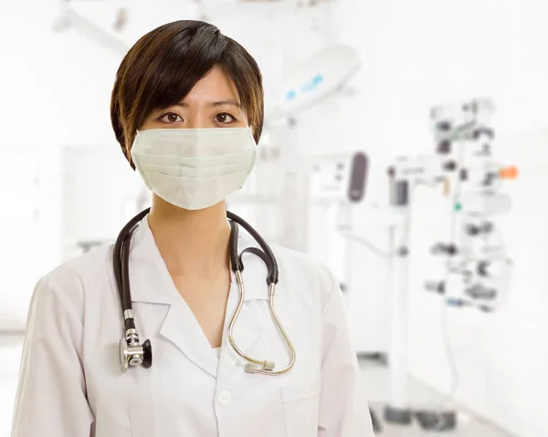 Asian female doctor with surgical mask looking at camera in clin — Stock Photo, Image