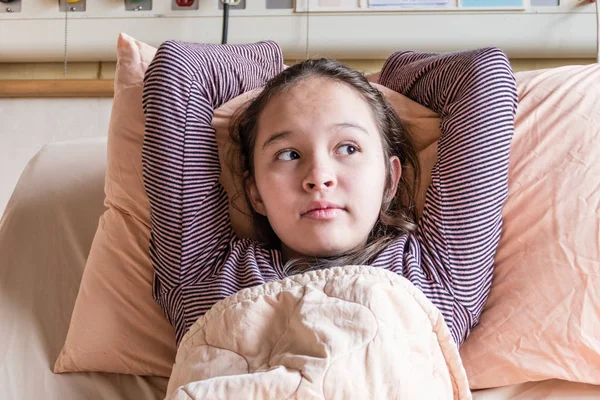 Asian American tween girl in hospital bed