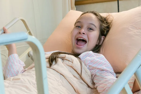 Rindo mestiço tween menina na cama do hospital — Fotografia de Stock