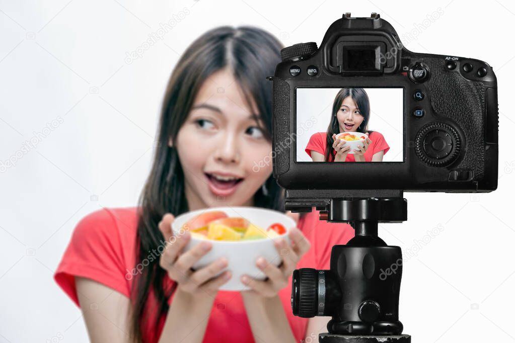 Asian food vlogger with fruit salad behind camera