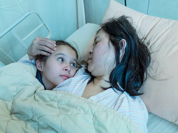 Mãe e filha deitadas na cama hosital juntas — Fotografia de Stock