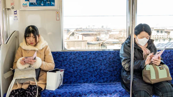 Japanese girl uses smartphone on train — ストック写真