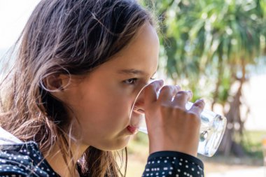 Tween girl drinks glass of water 