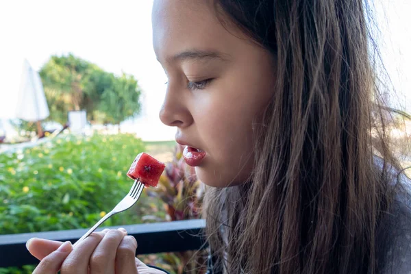 Tween girl eats watermelon with a fork