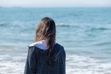Kız arkadan denize bakıyor.