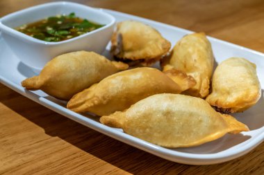 Beyaz tabakta Çin mantısı ve sos.