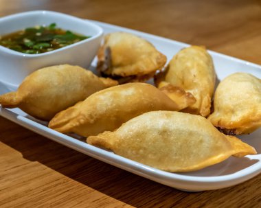 Beyaz tabakta Çin mantısı ve sos.