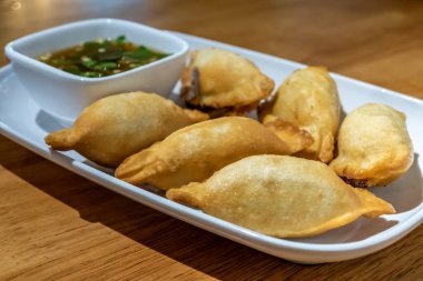 Beyaz tabakta Çin mantısı ve sos.