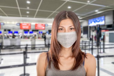 Arka planda odaklı havaalanı olmayan cerrahi maske takan Çinli bir kadın.