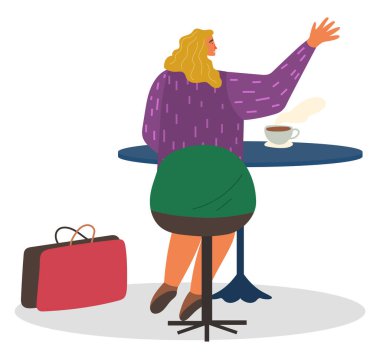 Kahve evinde oturan ve kahve içen bir kadın.