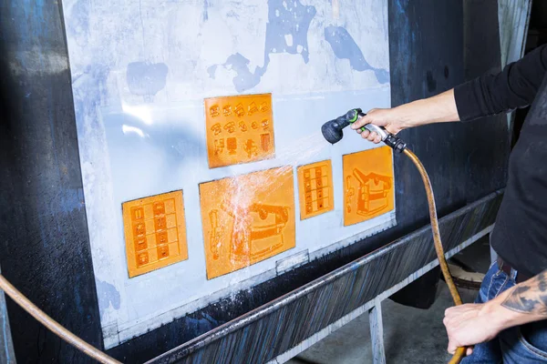 Uomo stampa pulizia muore con un tubo dell'acqua. Lavorare in una fabbrica di scatole di cartone . — Foto Stock