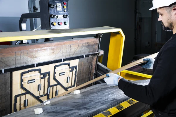 Kağıt kesme makinesi operatörü çalışırken öldü. Yumruk makinesine bir karton koymak. Karton kutu fabrikası.. 