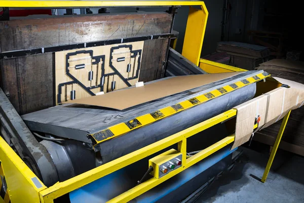 A punching machine in a cardboard boxes factory production hall. Paper die cutting machine.