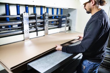 Karton kutu üretimi. Elinde kartonlar tutan kasklı bir işçi..