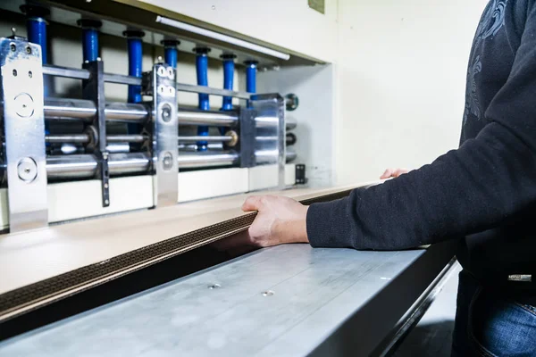 Παραγωγή χαρτοκιβωτίων. Εργάτης κρατά χαρτοκιβώτια στα χέρια του σε μια αίθουσα παραγωγής σε ένα εργοστάσιο. — Φωτογραφία Αρχείου