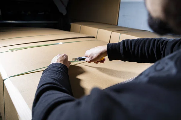 Un uomo che usa un coltello per aprire una scatola di cartone. Apertura pacchetti. Unboxing . — Foto Stock