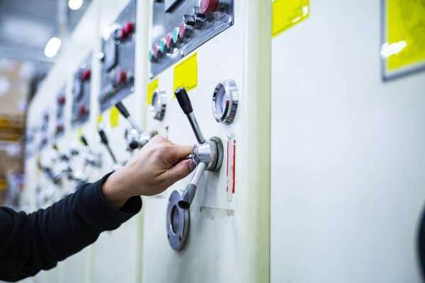 Male worker operates printers in a production hall. Inputing printing settings. Printing house.