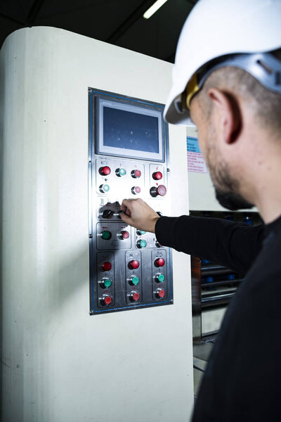 Pushing the button on a control panel. Machines operator in a production hall in a factory.